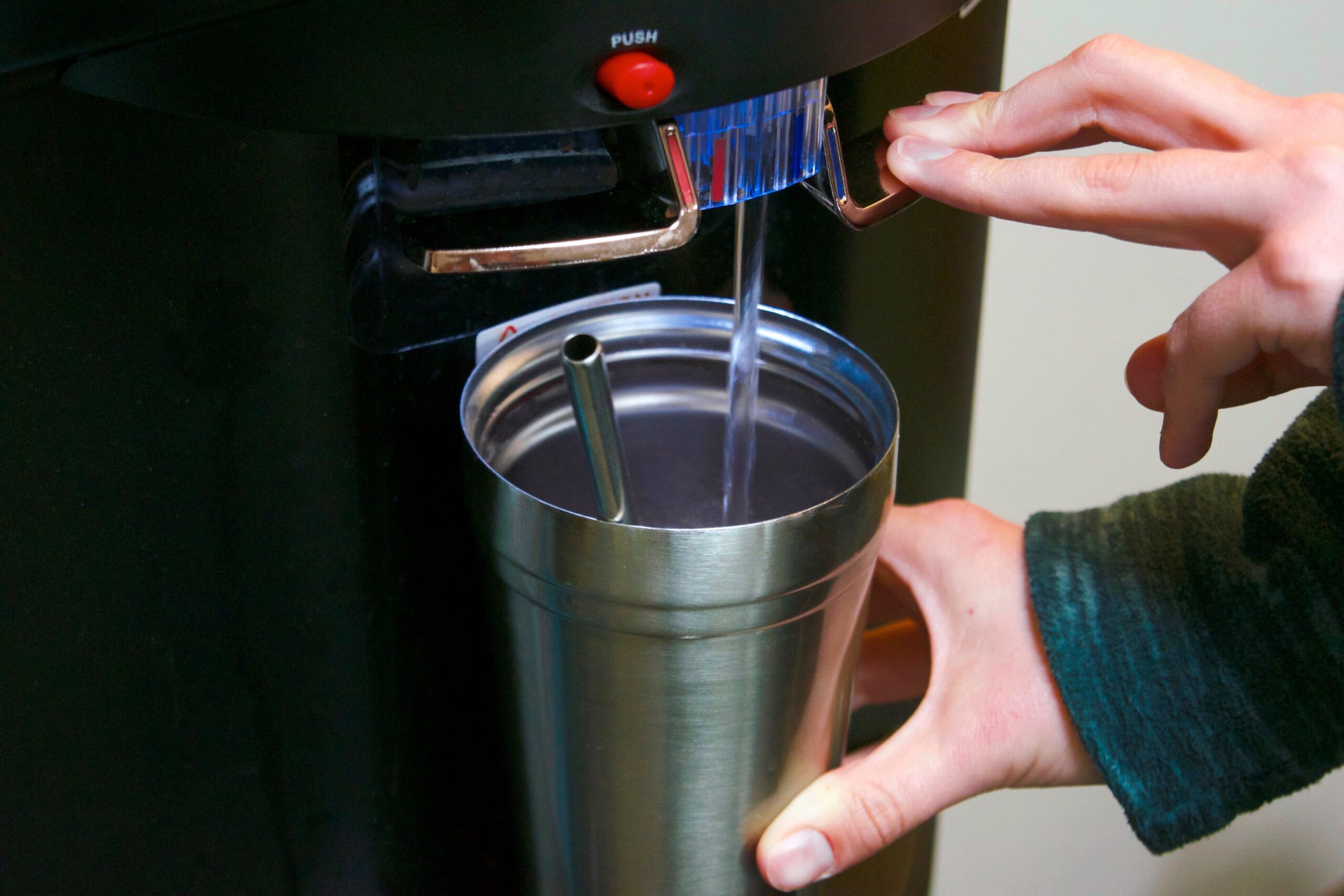 employee filling cup at bottleless water cooler